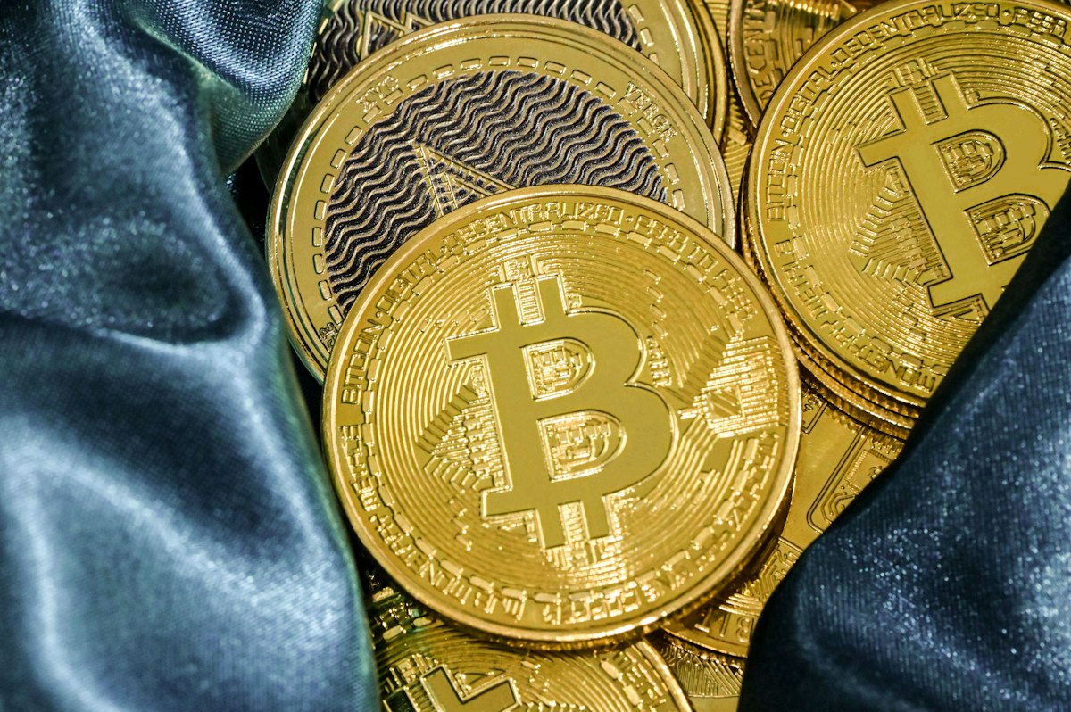 Physical cryptocurrency tokens on blue fabric, used as an editorial illustration